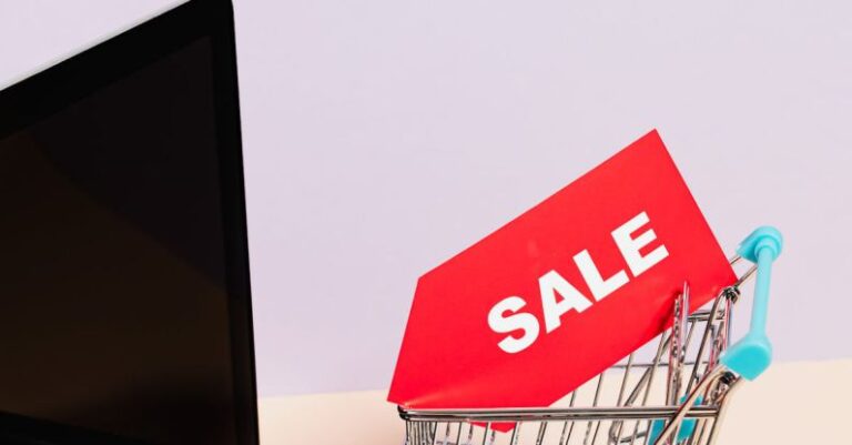 Deduction - A Red Sale Tag on a Miniature Shopping Cart Placed on a Macbook Laptop