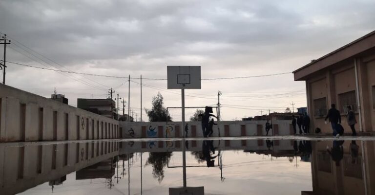 School Districts - Cloudy sky reflecting in water of huge puddle on basketball playground located on territory of school