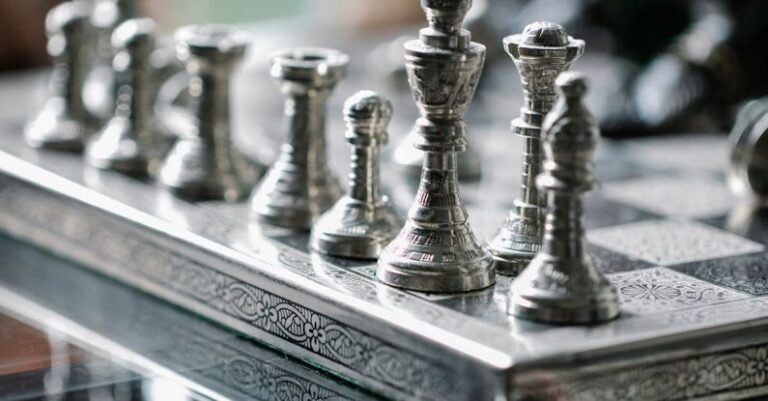 Improvements - Classic metal chess board with set figurines designed with carved ornaments and placed on glass table in light room